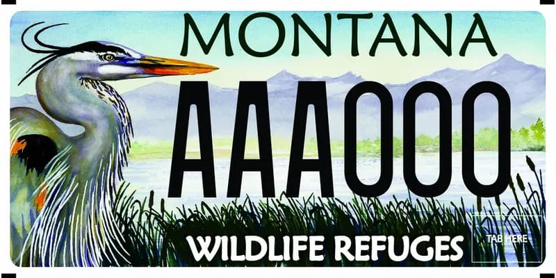 A license plate with black and white text. Illustration of crane among wetlands with mountains in background. Bottom says Wildlife Refuges.