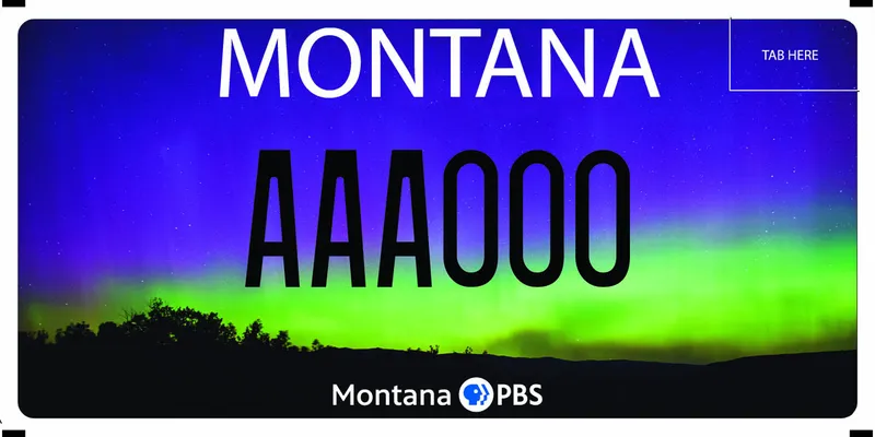 A license plate with black and white text. An Aurora borealis filled sky with silhouette landscape bottom. Bottom says Montana PBS.