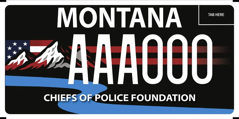 A black license plate with white text. American flag, mountains, and river graphics. Bottom says chiefs of police foundation.