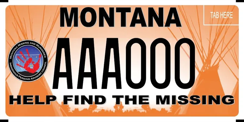 An orange license plate with teepees and poles in distance and black text. Montana Missing and Murdered Indigenous Person Advisory Council logo is on left side of plate. Bottom says Help Find the Missing.
